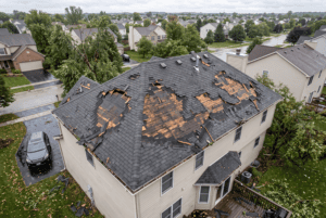 Aerial view showing storm-damaged roof with multiple missing shingle sections or noticeable damage